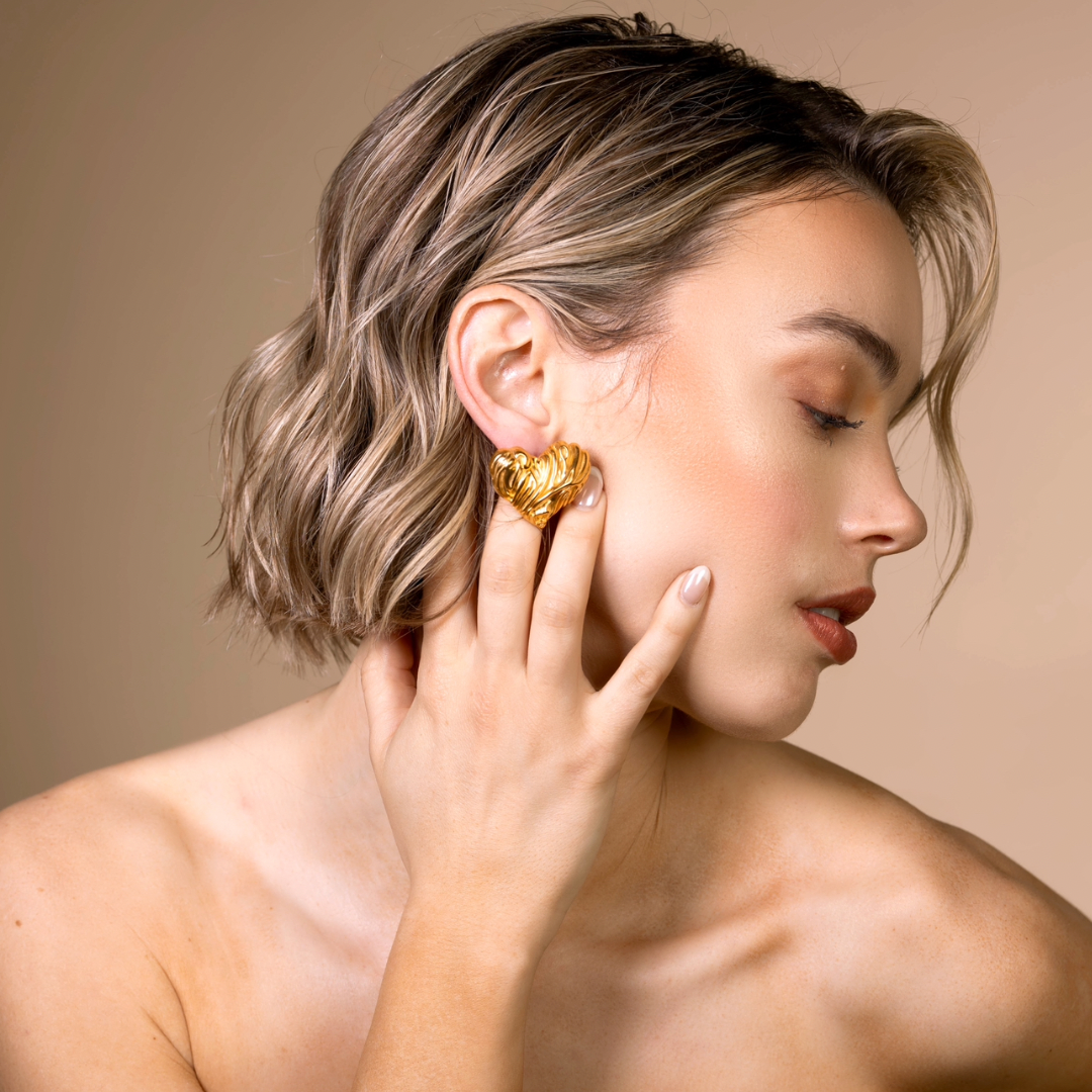 Amora heart hypoallergenic gold earring close up on model side photo