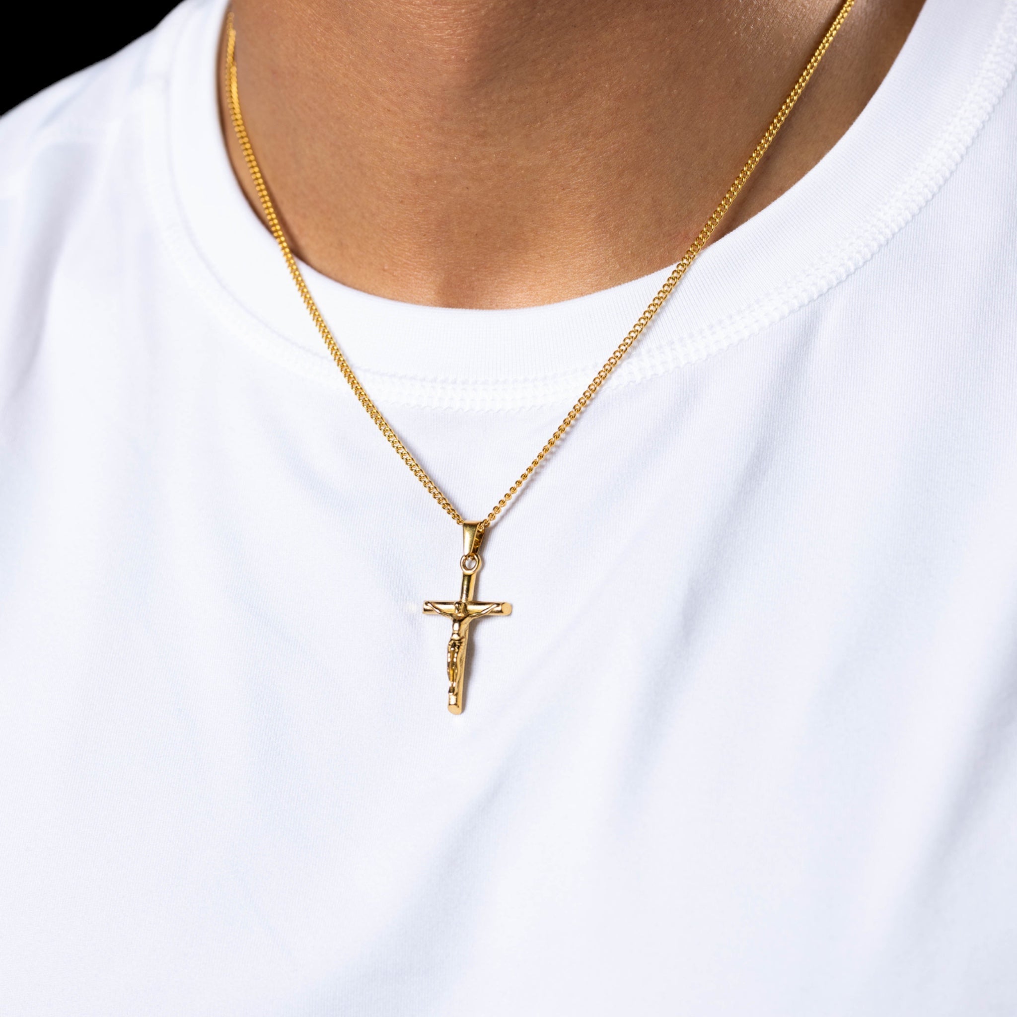 Gold crucifix jesus necklace 18 karat hypoallergenic with chain close-up worn on a model photo