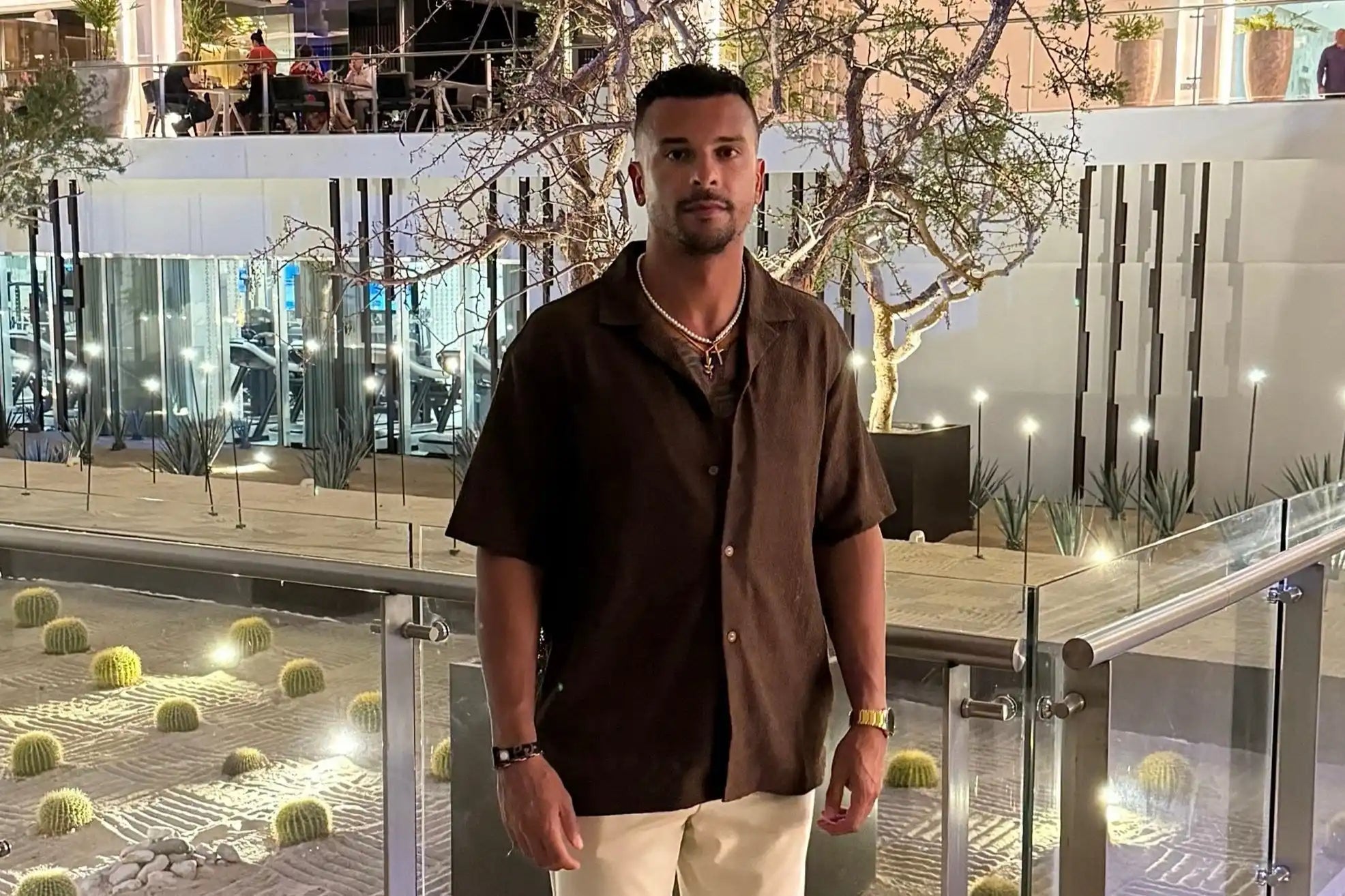 A person wearing a brown short-sleeved button-up shirt and light-colored pants.